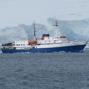 Le bateau UShuaia vu de profil naviguant devant un glacier géant