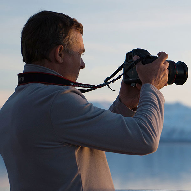 un homme prend un film avec son appareil photo digital à bord d'un bateau en antarctique