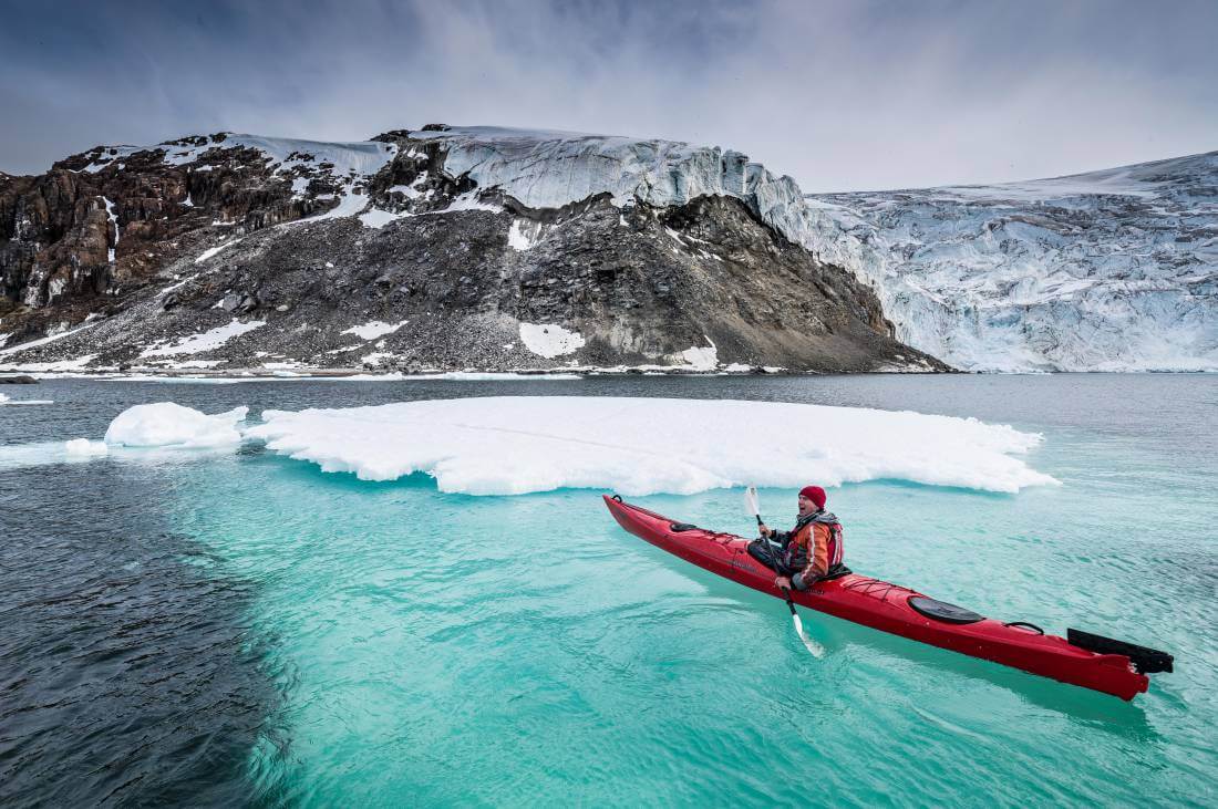 kayak au bord d'un iceberg dans les eaux transparentes