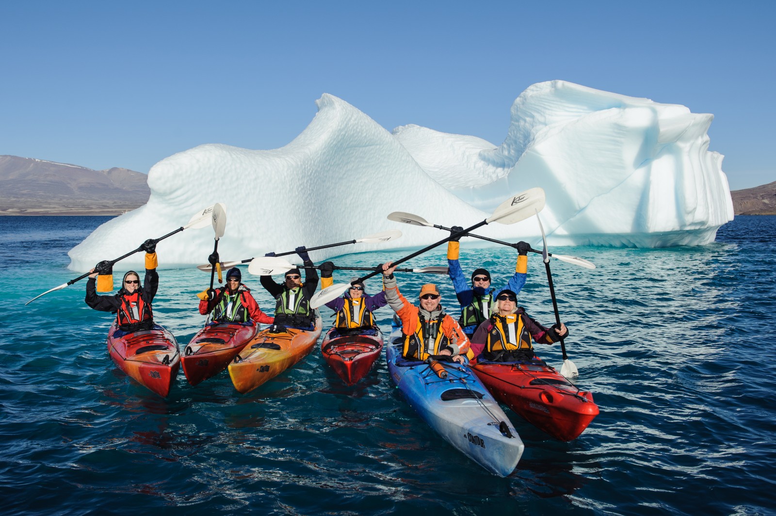 groupe de kayakiste devant un iceberg