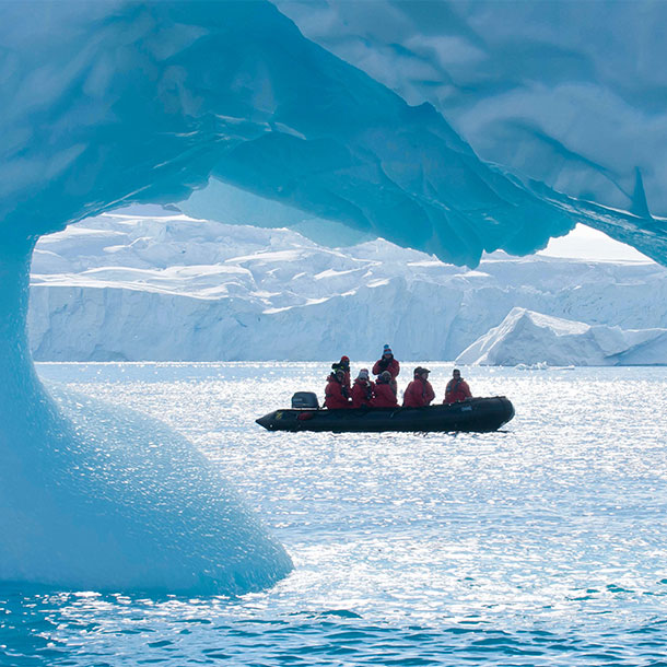 un zodiac devant un iceberg