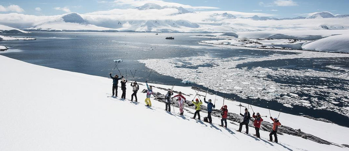 des randonneurs en antarctique sur la neige avec la baie en arrière plan