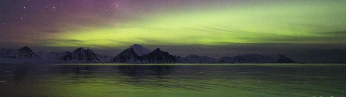 photo panoramique d'une aurore australe avec la chaine de montagne de l'antarctique