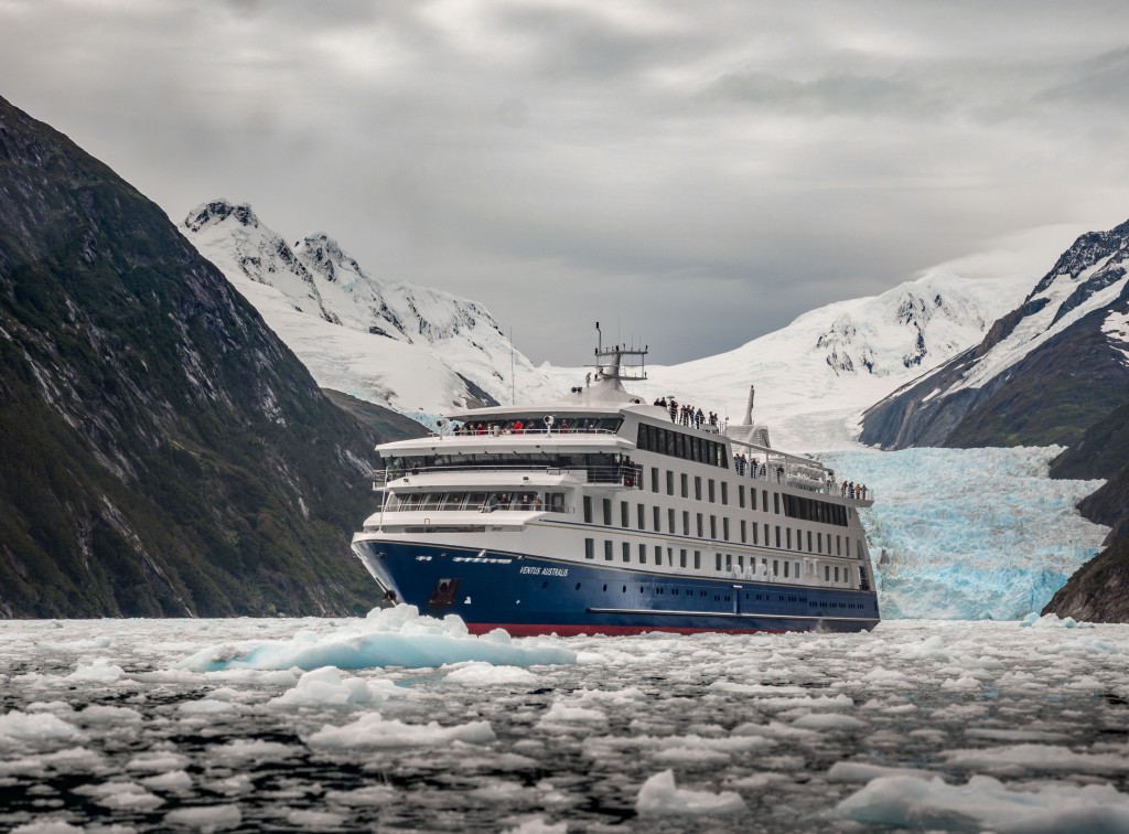 Le bateau Ventus Australis vu de 3/4 dans une mer de glace avec un glacier en fond de tableau
