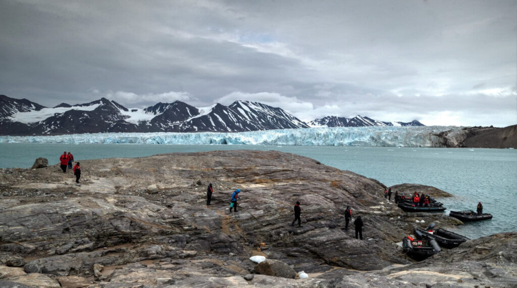 des voyageurs se promènent dans un paysage du Spitzberg avec montagnes et glacier