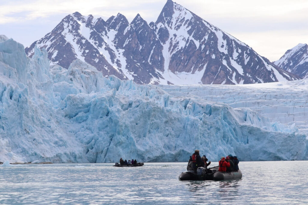 deux zodiac avec des voyageurs observent le front d'un glacier