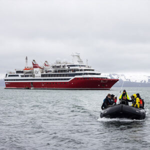 un zodiac arrive en face avec le bateau Exploris One en fond