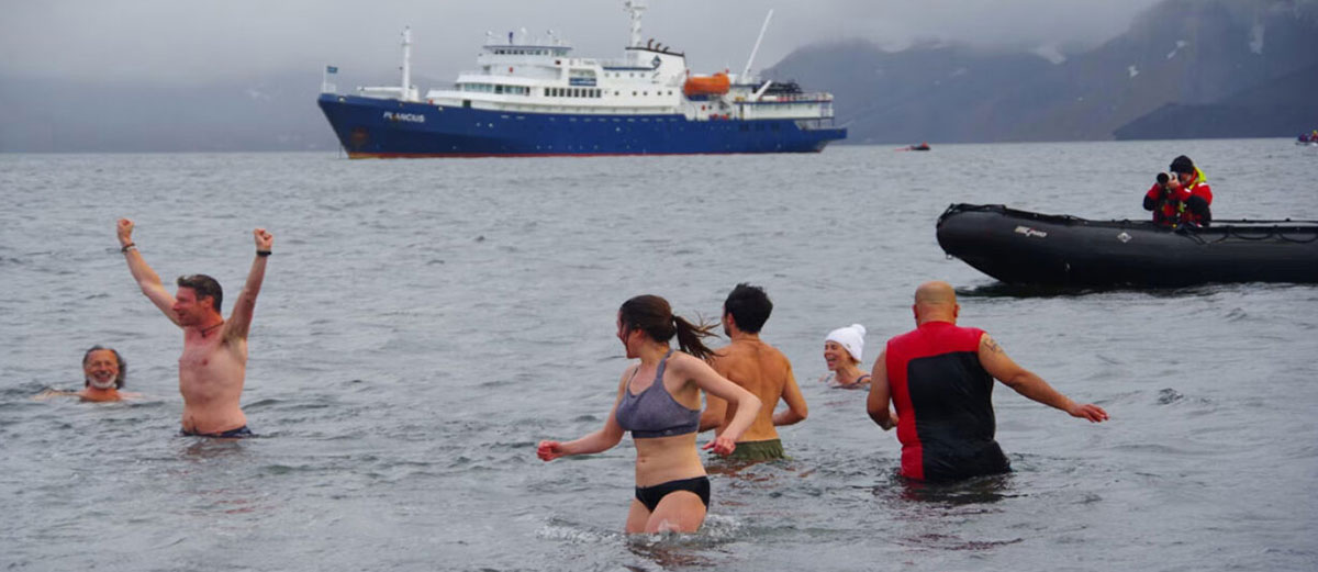 baignade polaire de quelques personne avec le bateau en arrière plan
