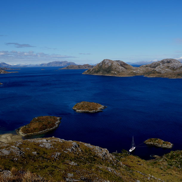 le voilier au mouillage vu depuis la falaise avec l'archipel du Horn en arrière plan
