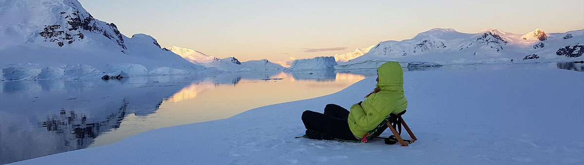un homme assis sur la neige ne antarctique contemple le paysage au coucher du soleil